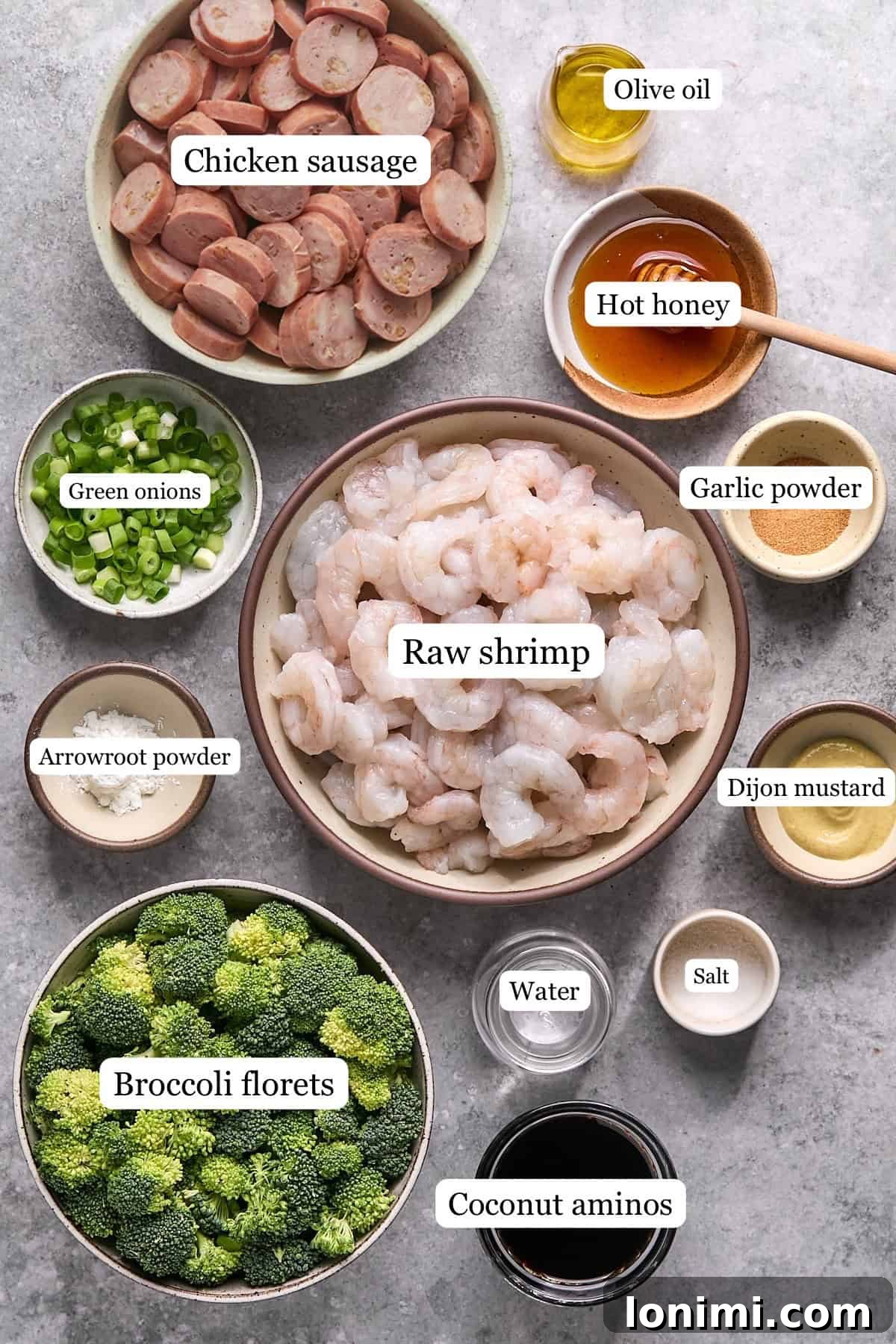Gluten Free Hot Honey Glazed Shrimp and Sausage Stir Fry 3 A collection of fresh ingredients artfully arranged in small bowls, including sliced chicken sausage, raw shrimp, vibrant broccoli florets, and the distinct hot honey sauce ingredients.