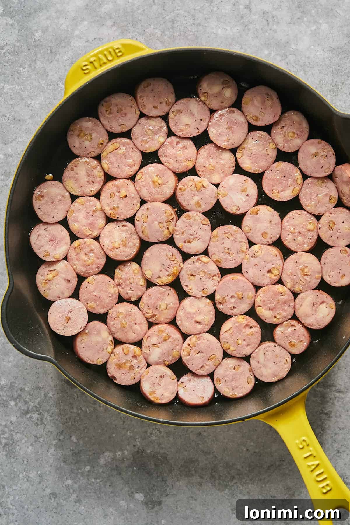 Gluten Free Hot Honey Glazed Shrimp and Sausage Stir Fry 6 Perfectly sliced chicken sausages browning in a single layer in a bright yellow Staub skillet, sizzling over medium-high heat.