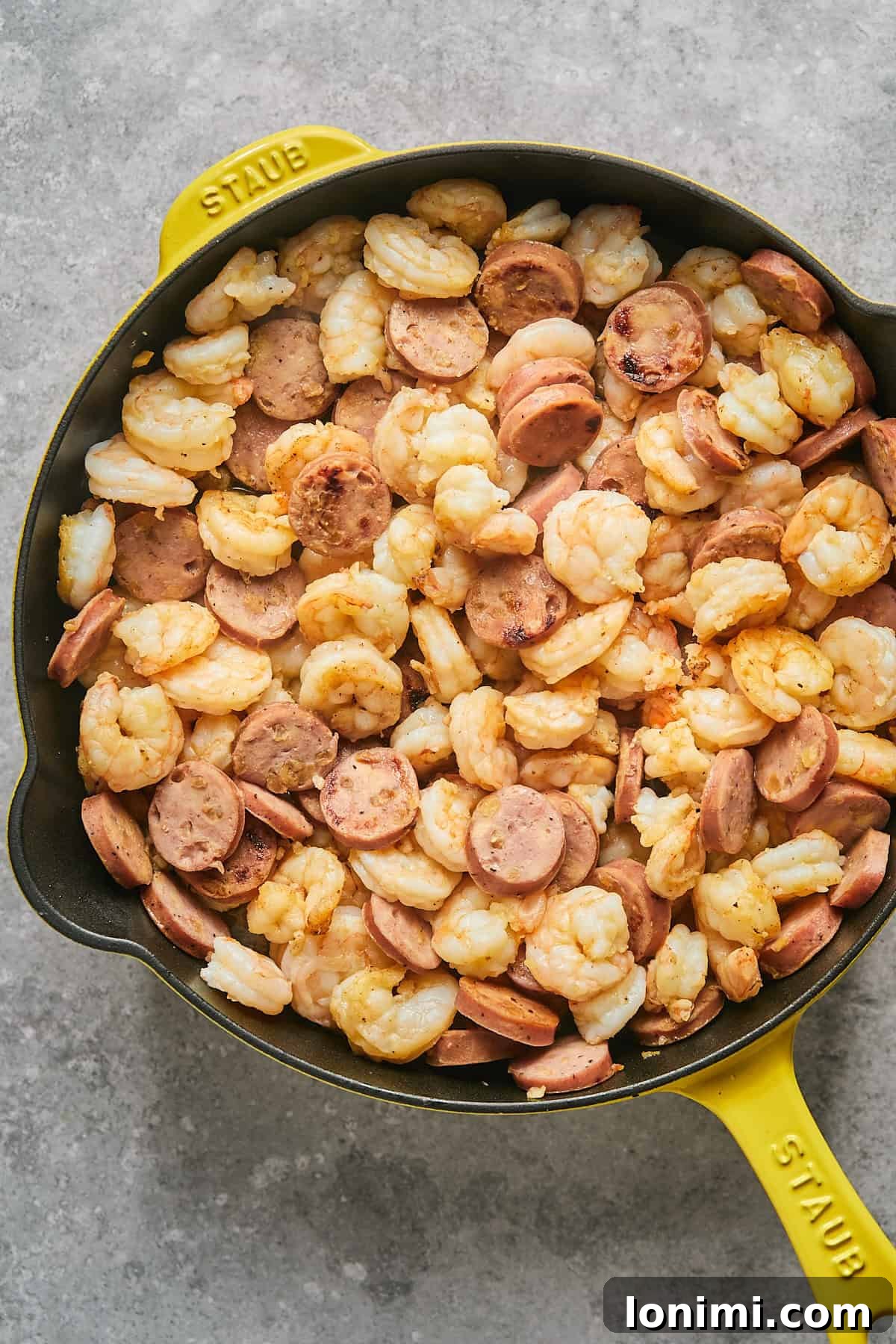 Gluten Free Hot Honey Glazed Shrimp and Sausage Stir Fry 7 Juicy shrimp added to the skillet with browned chicken sausage, creating a vibrant mix as they begin to cook together.