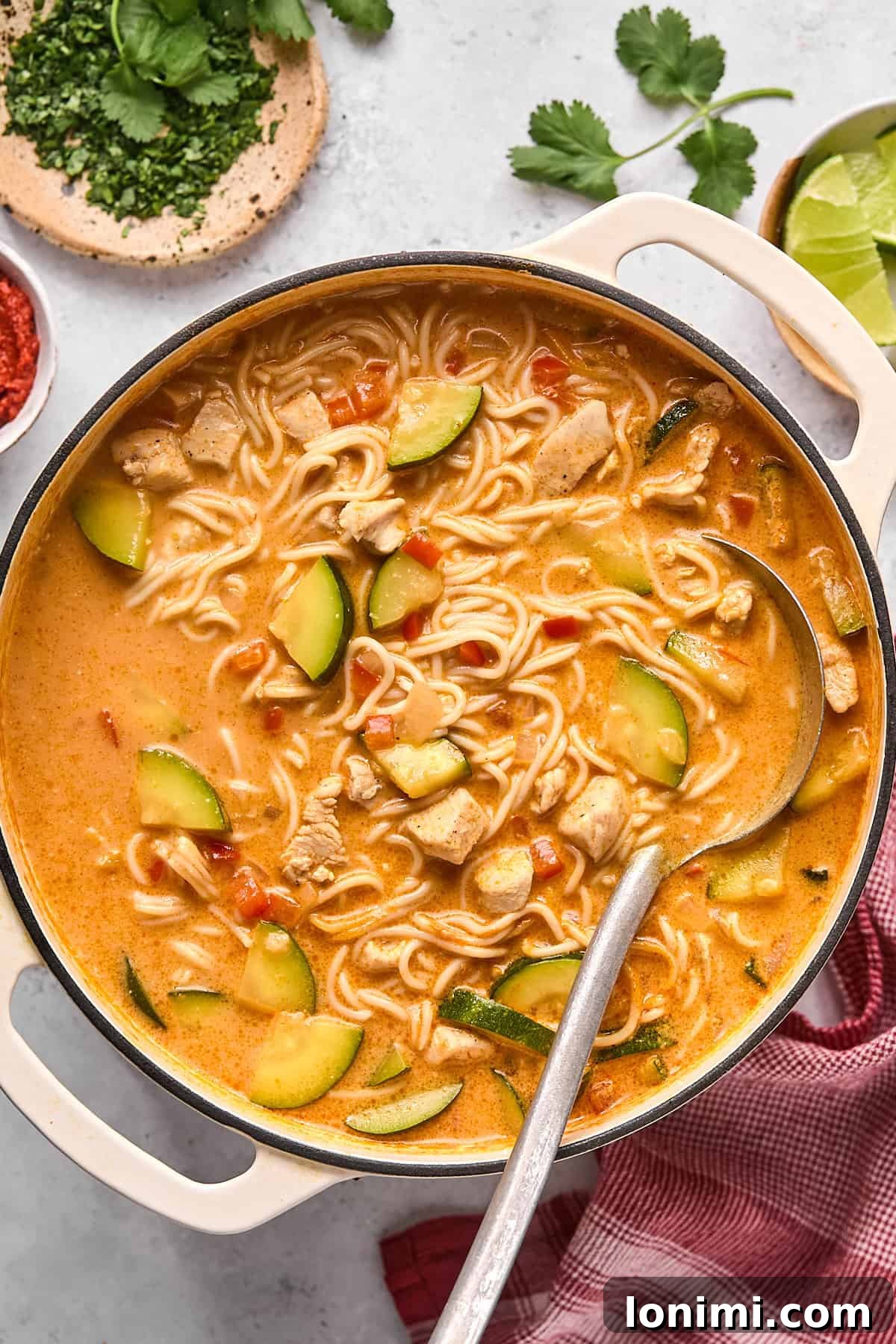 Thai noodle soup in a pot with a serving ladle