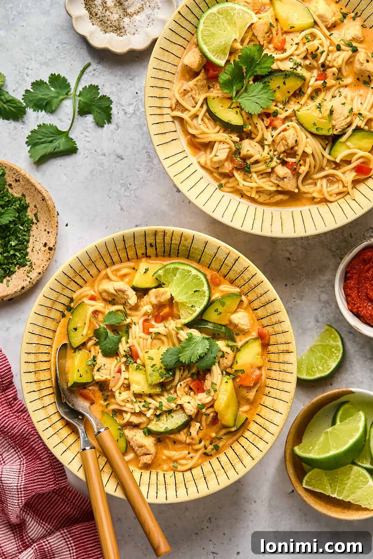 two bowls of soup topped with limes and cilantro 