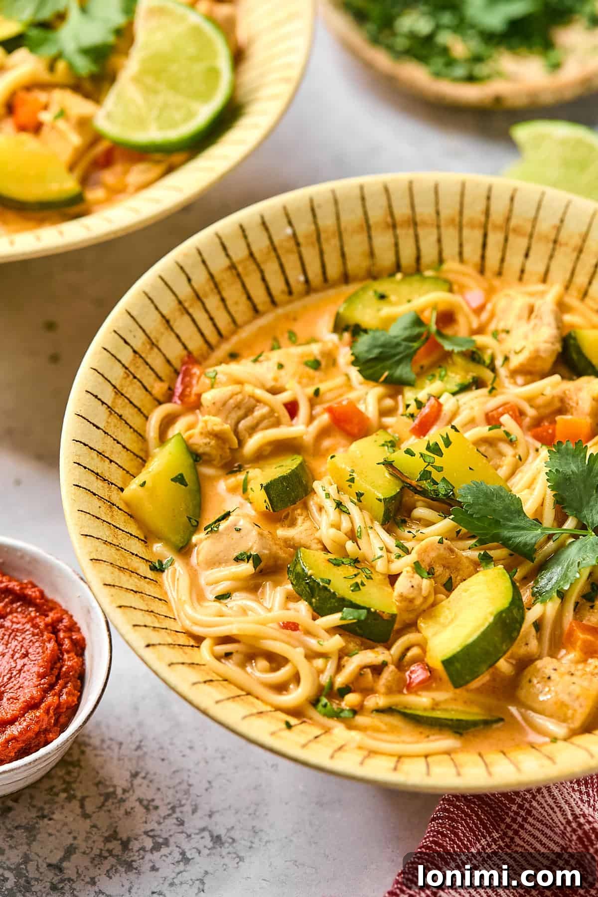 a side view of red curry soup in a bowl 