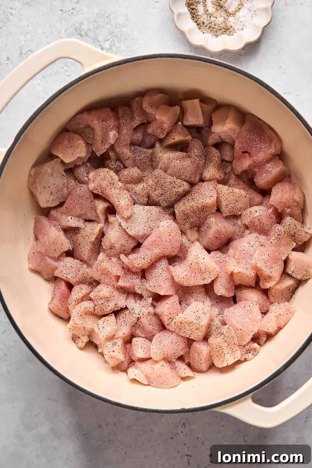 raw chicken pieces in a white dutch oven pot