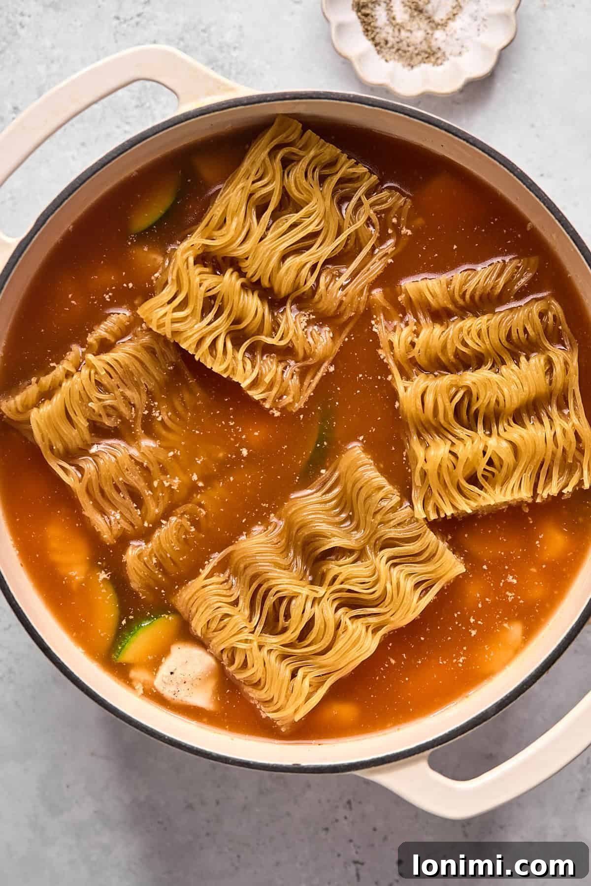 noodles and broth and chicken in a pot