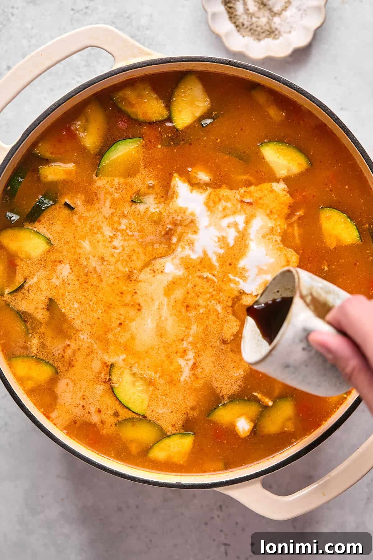 Thai soup with coconut milk being poured into a pot