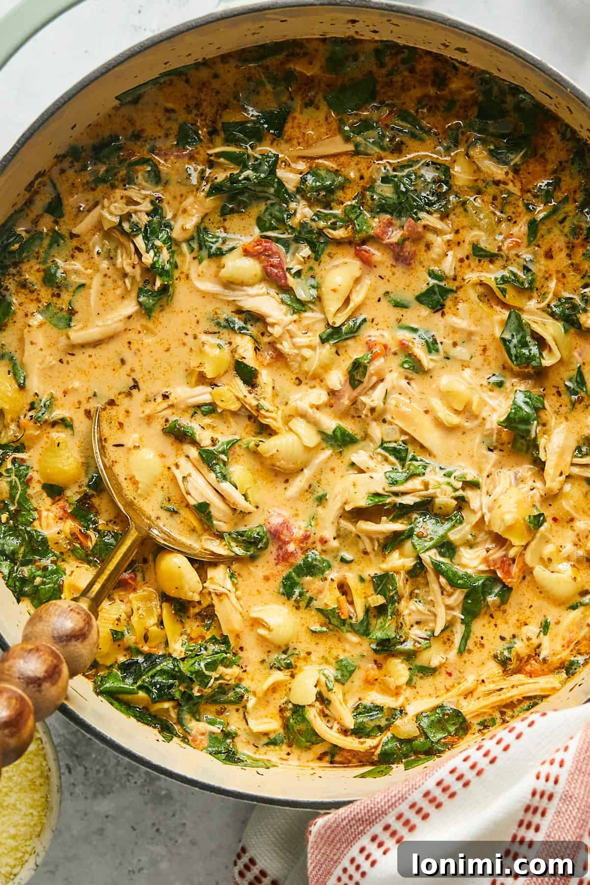 A large Dutch oven filled with the creamy, rich Marry Me Chicken Soup, with a gold ladle resting on the side, inviting you to serve yourself.