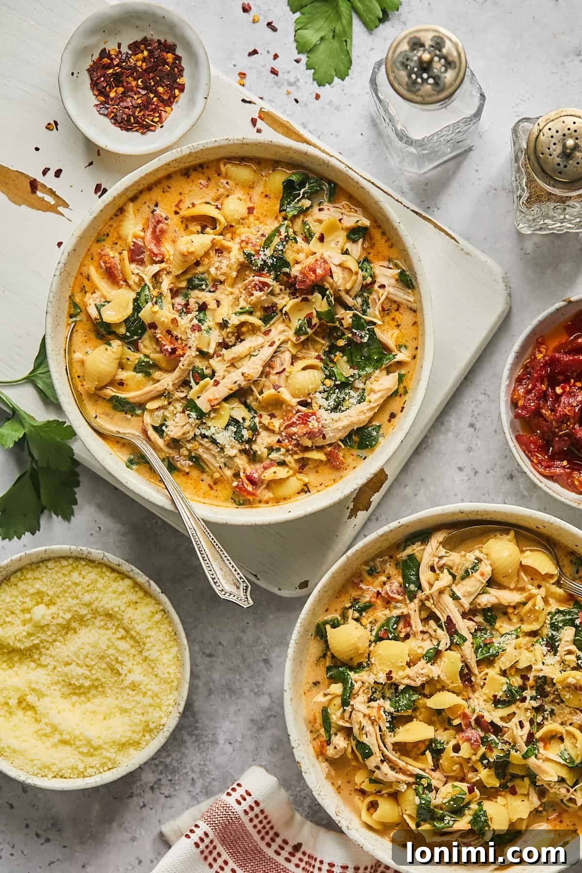 Two steaming bowls of Marry Me Chicken Soup, richly garnished with fresh Parmesan cheese and herbs, presented beautifully for serving.