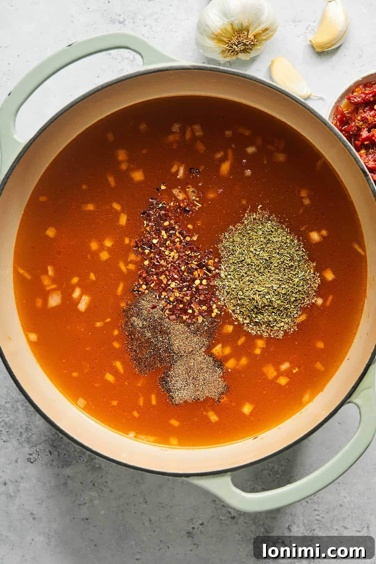A pot of simmering broth with various spices and seasonings added, creating a fragrant and flavorful liquid base.