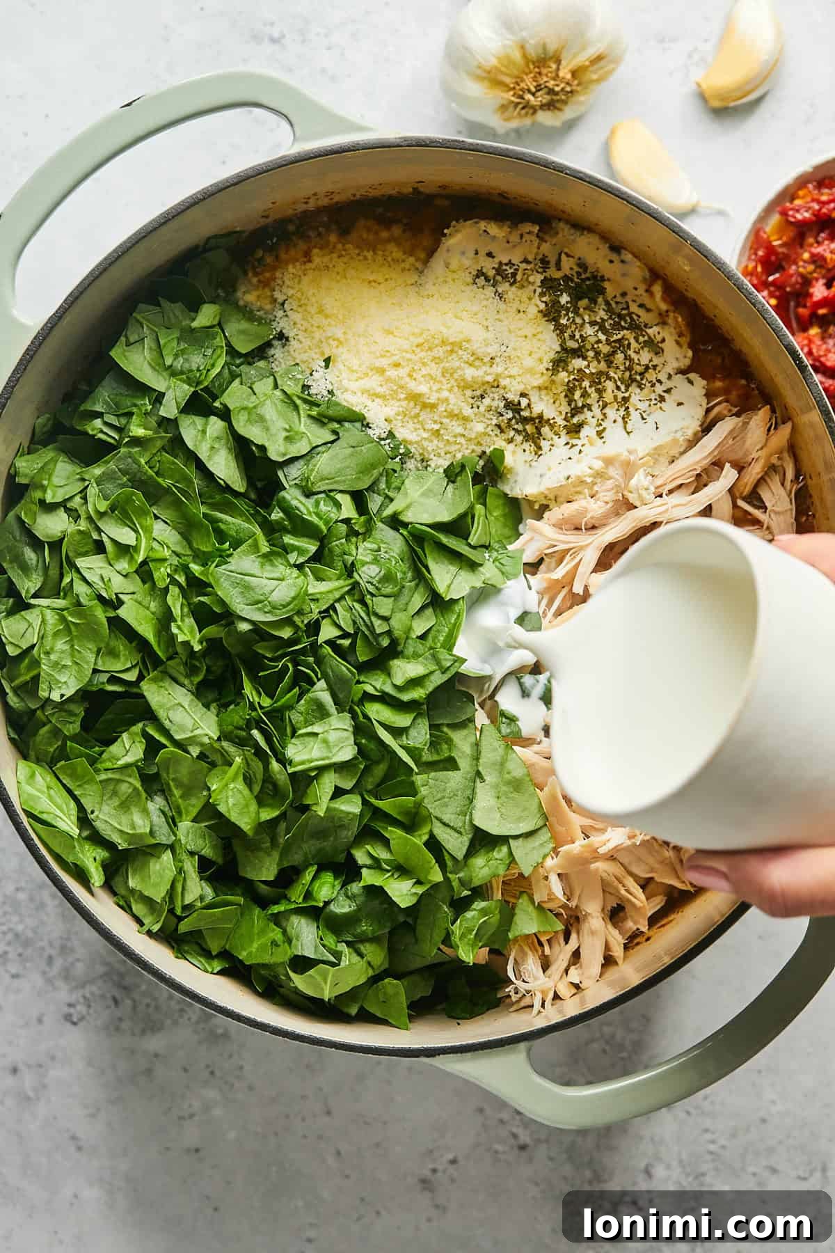Shredded chicken, fresh spinach, half & half, Boursin cheese, and Parmesan cheese being added to the simmering soup, preparing for its creamy transformation.