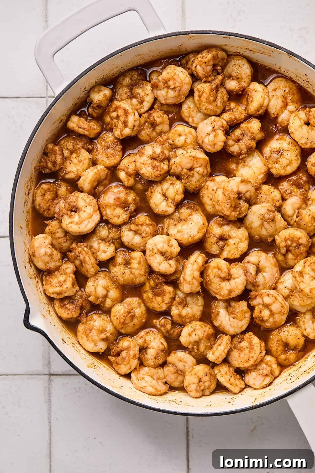 Perfectly cooked, seasoned shrimp in a cast iron skillet, displaying a vibrant pink color and a slight char.
