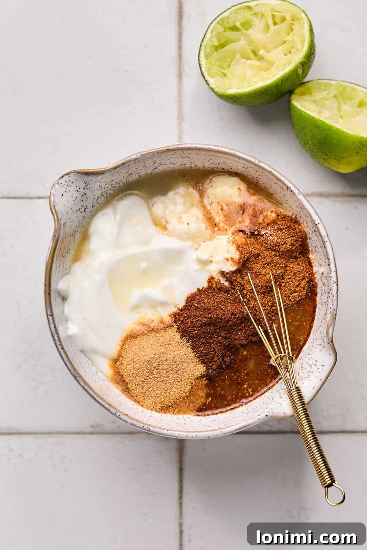 A selection of Baja sauce ingredients, including Greek yogurt, mayonnaise, and fresh limes, arranged in a bowl, ready to be mixed.