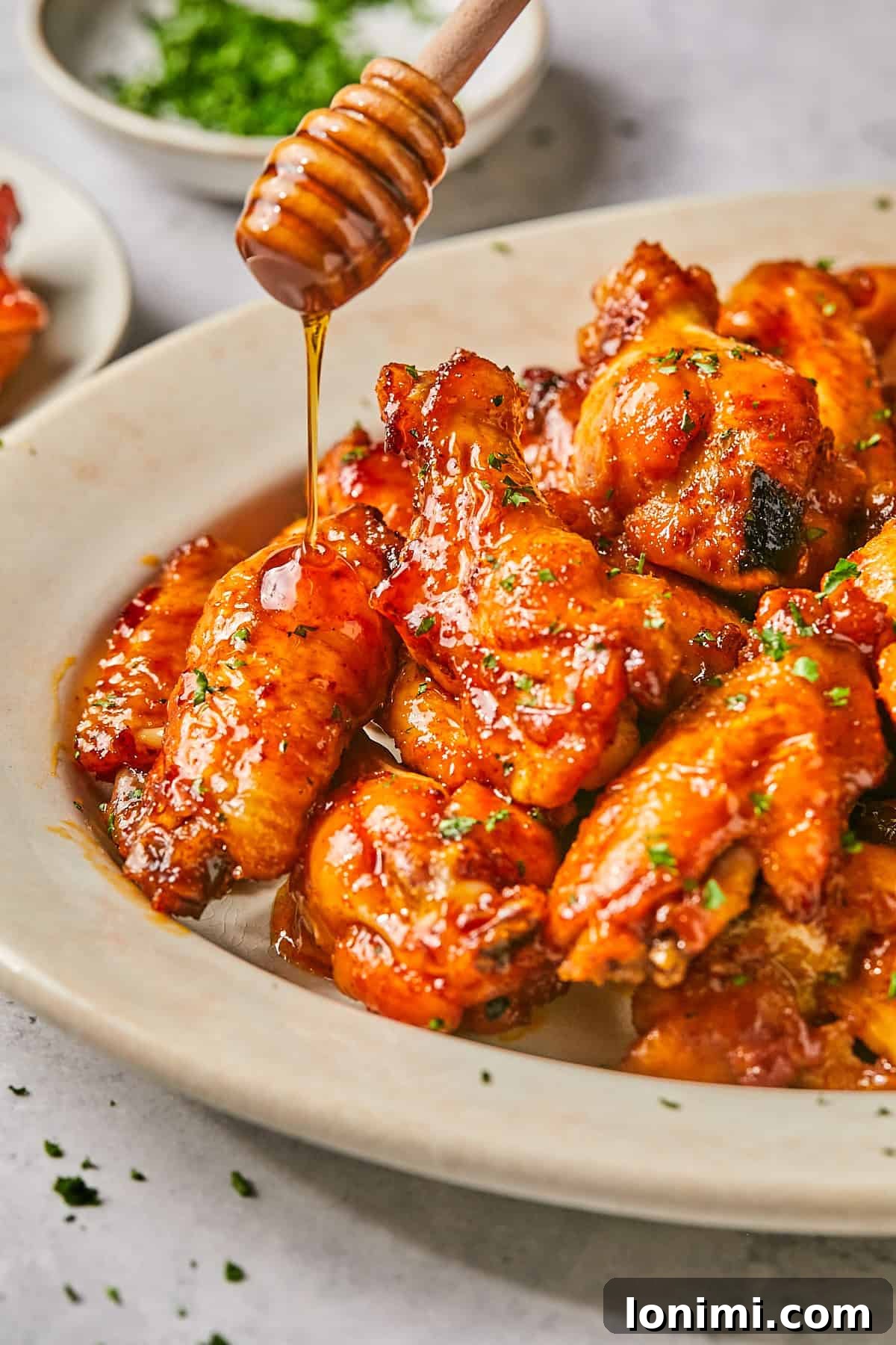 hot honey chicken wings on a platter with honey being drizzled on top