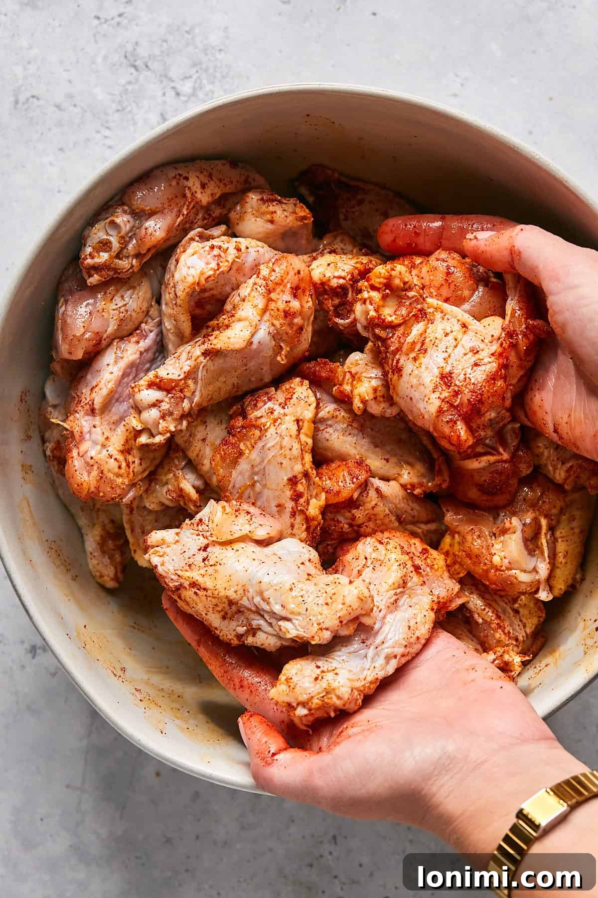 chicken wings being tossed with oil and seasonings