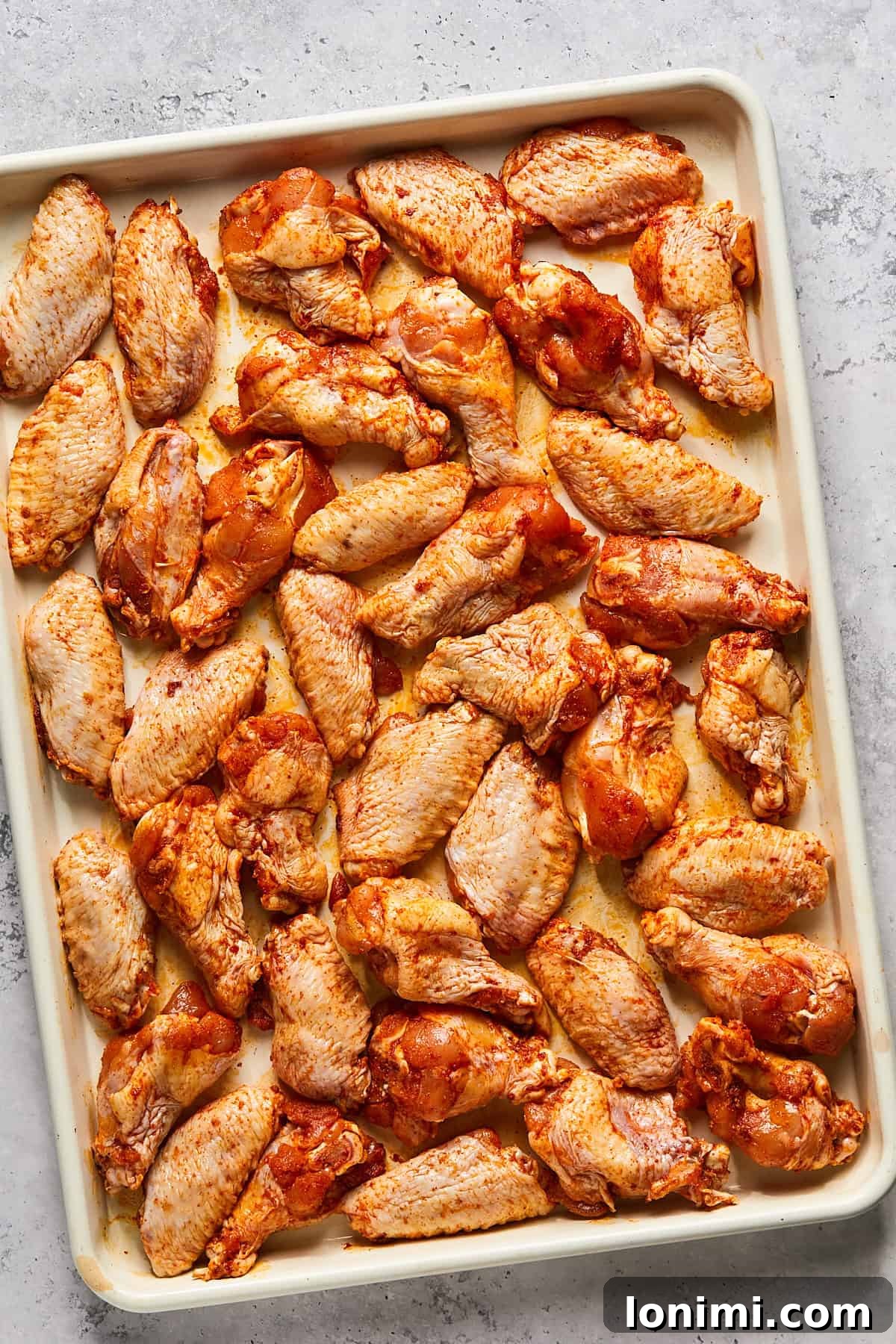 raw chicken wings spread out on a baking sheet