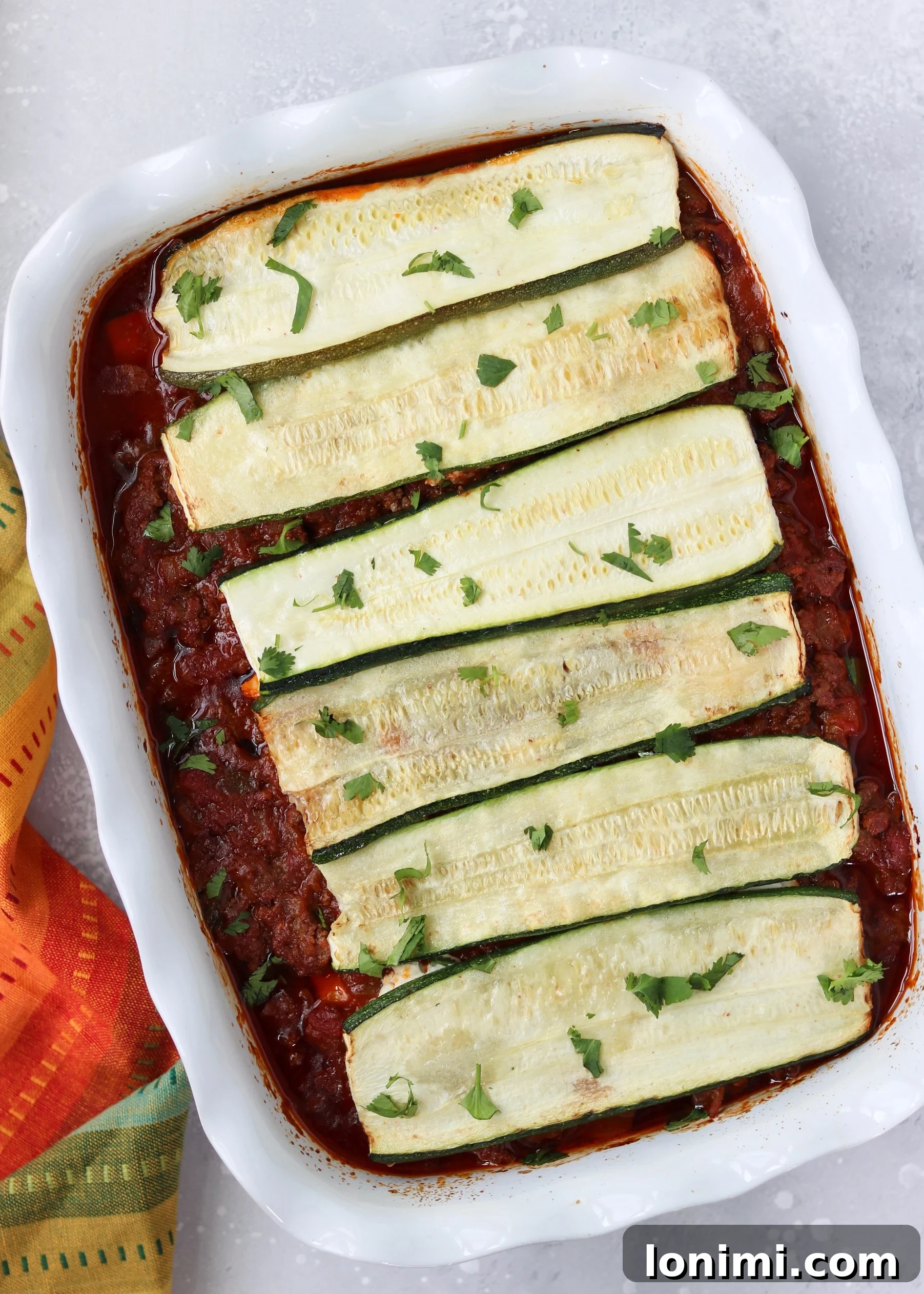 Deliciously baked Paleo Mexican Lasagna sliced and ready to serve, showcasing layers of zucchini and meat sauce.