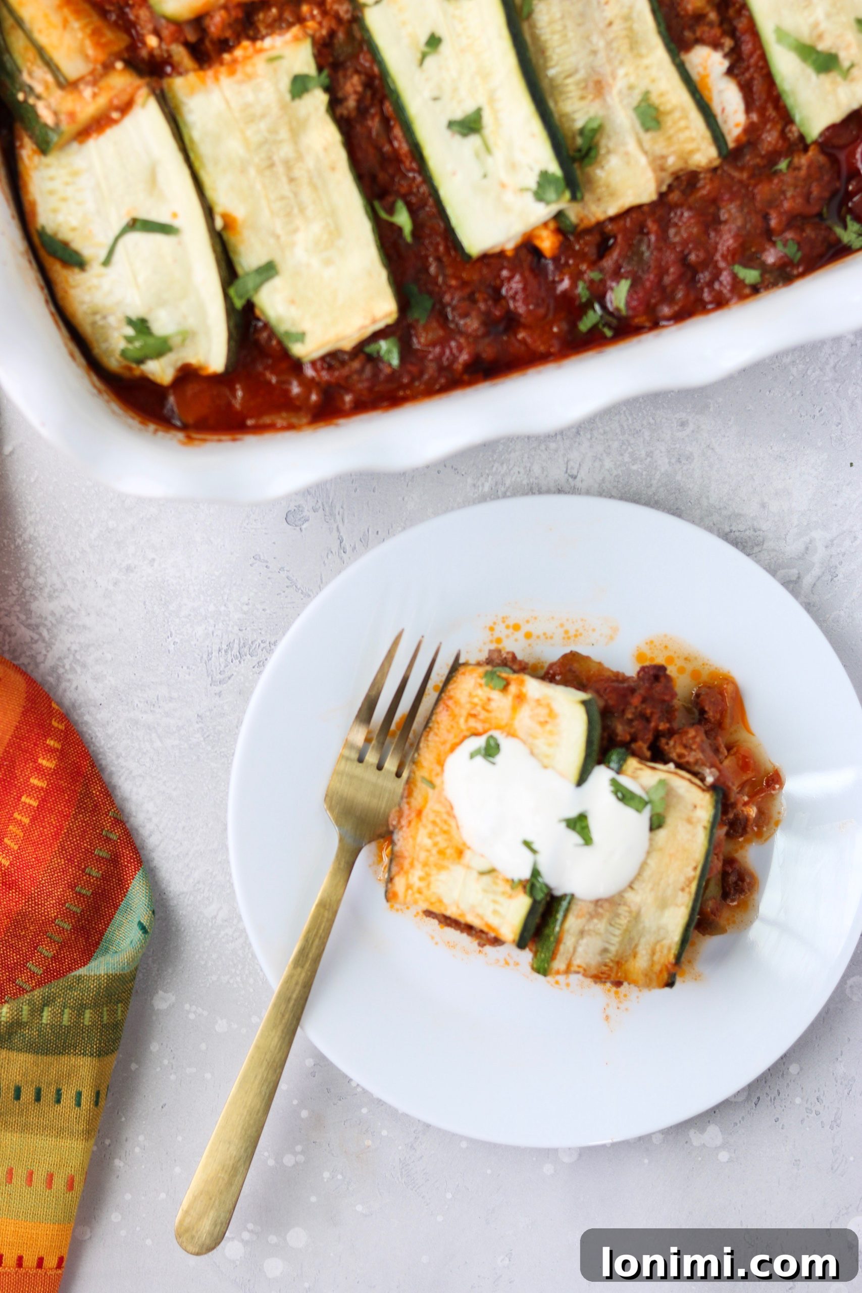 Unbaked Paleo Mexican Lasagna, showing distinct layers of zucchini, meat sauce, and creamy dairy-free cheese dots, ready for the oven.