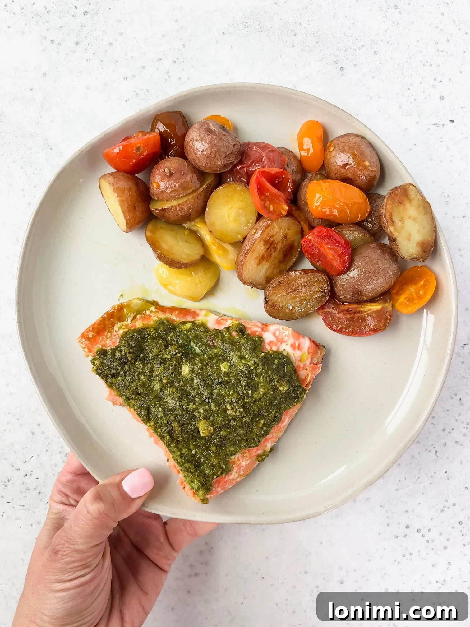 Sheet Pan Pesto Salmon ready to be served, showing potatoes and tomatoes.