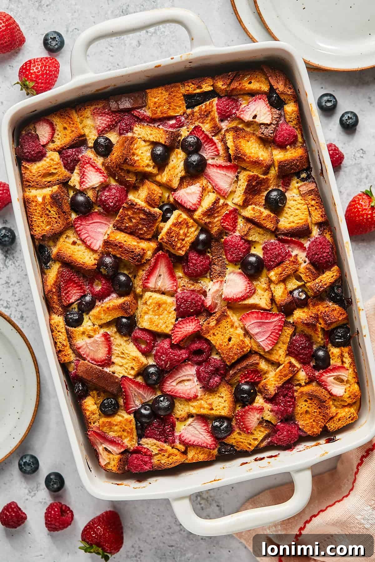a casserole dish filled with french toast and sliced berries. 