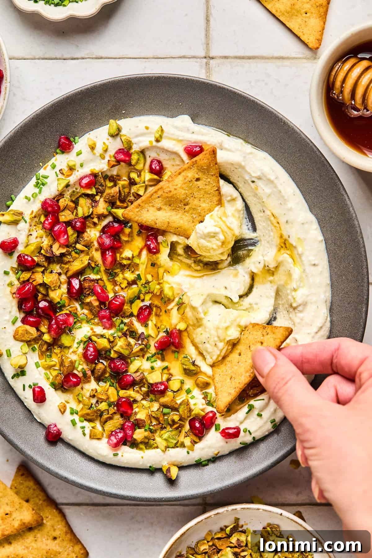 whipped feta with hot honey, pistachios, pomegranates and chives with a pita cracker dipping in