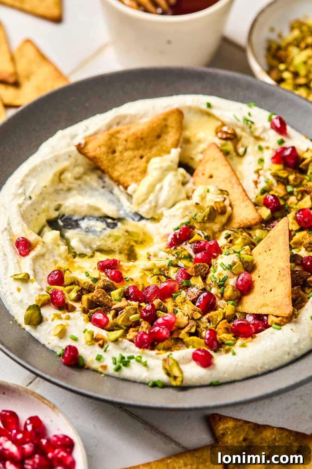 feta dip with pomegranates and pistachios with pita chips on top