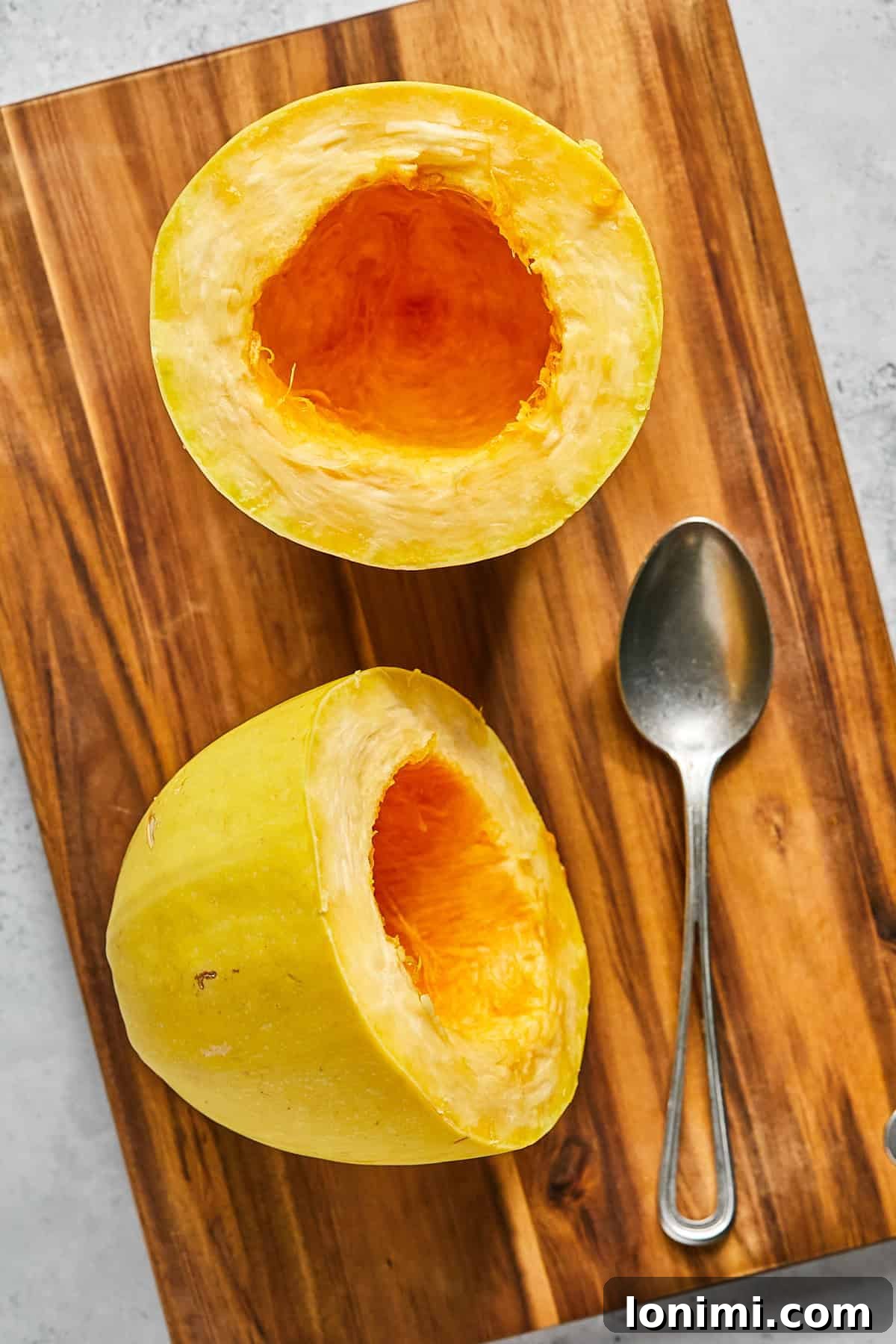 A spaghetti squash sliced cleanly in half, revealing its inner seeds, ready for scooping and roasting.