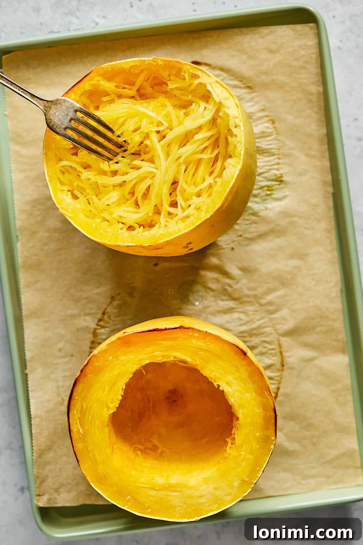 A fork being used to effortlessly noodle cooked spaghetti squash from its shell, showcasing its pasta-like strands.