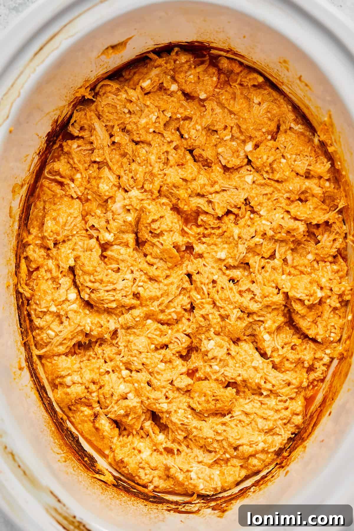 All ingredients combined and stirred thoroughly in the crock pot, creating a creamy, uniform buffalo chicken dip.