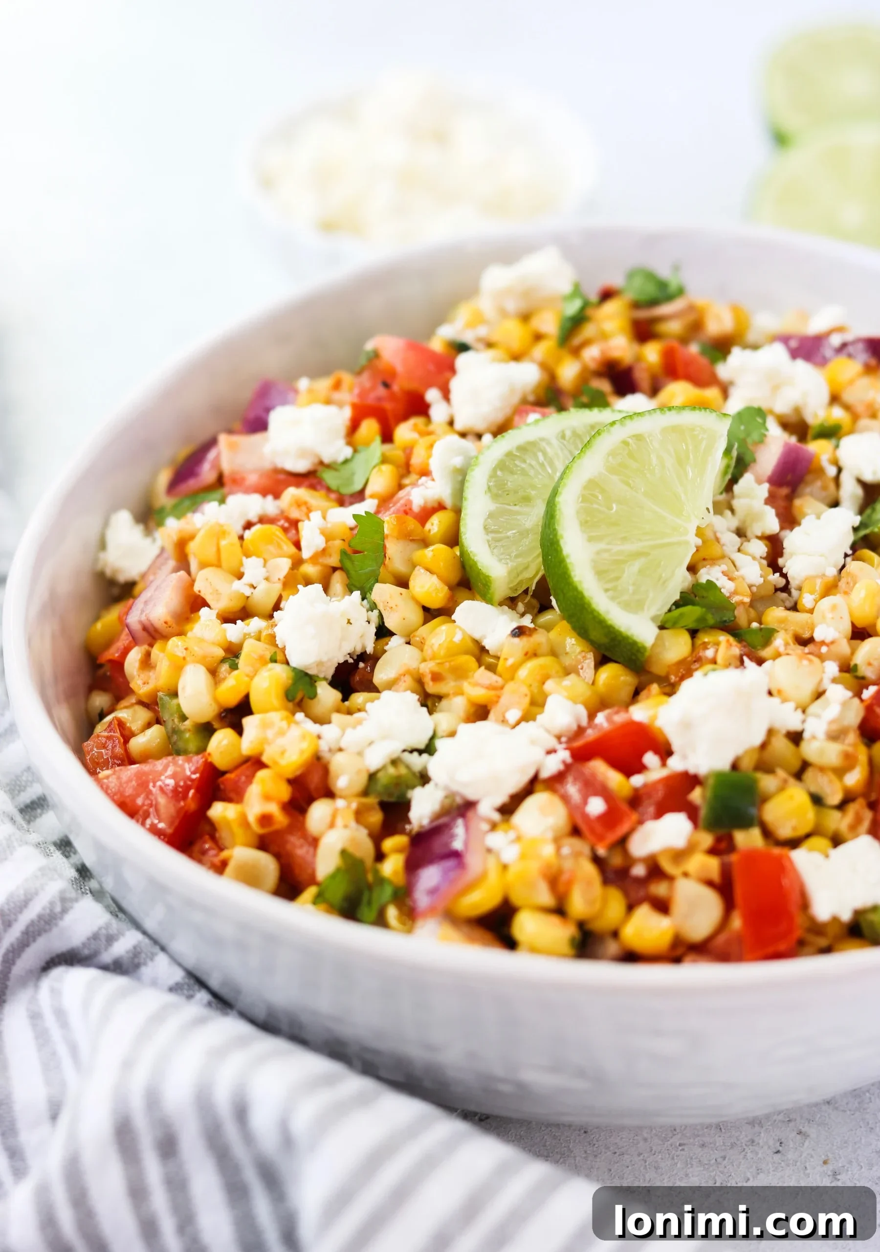 Close-up of the Mexican Street Corn and Tomato Salad, highlighting the charred corn kernels, diced tomatoes, and creamy dressing.