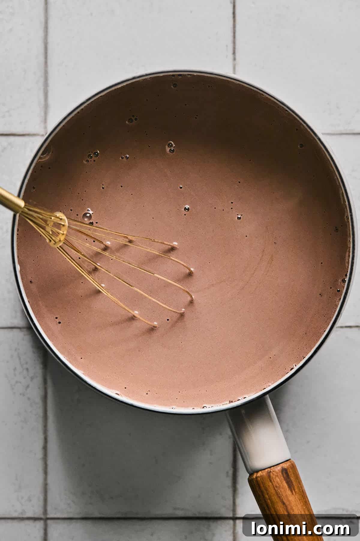 The fully combined and warmed protein hot chocolate mixture simmering gently in a saucepan, ready to be poured into a mug.