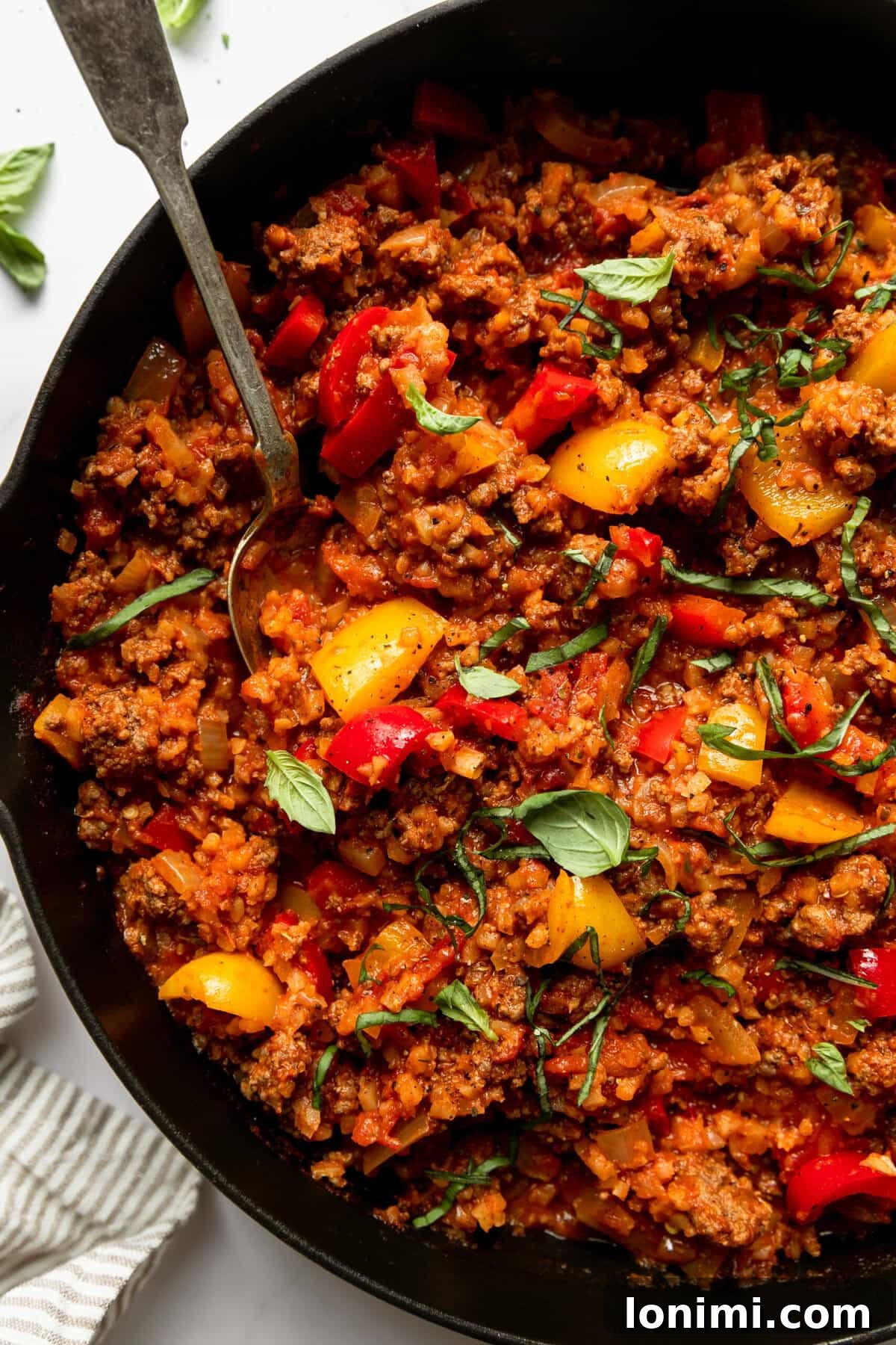 Close-up of the finished unstuffed pepper skillet, showcasing the rich blend of cauliflower rice, ground beef, and colorful peppers in a savory tomato sauce.