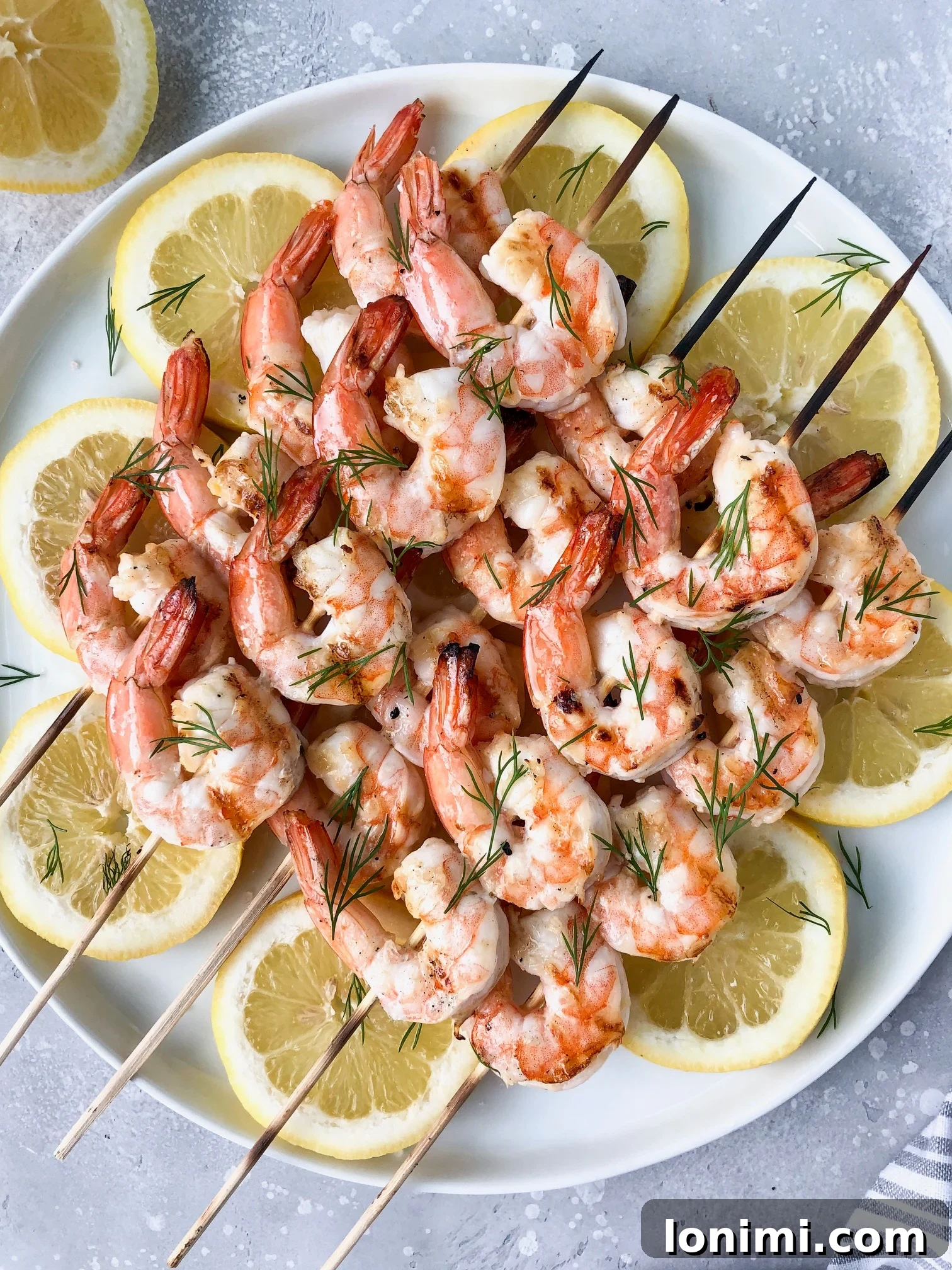 Grilled garlic butter dill shrimp threaded onto wooden skewers