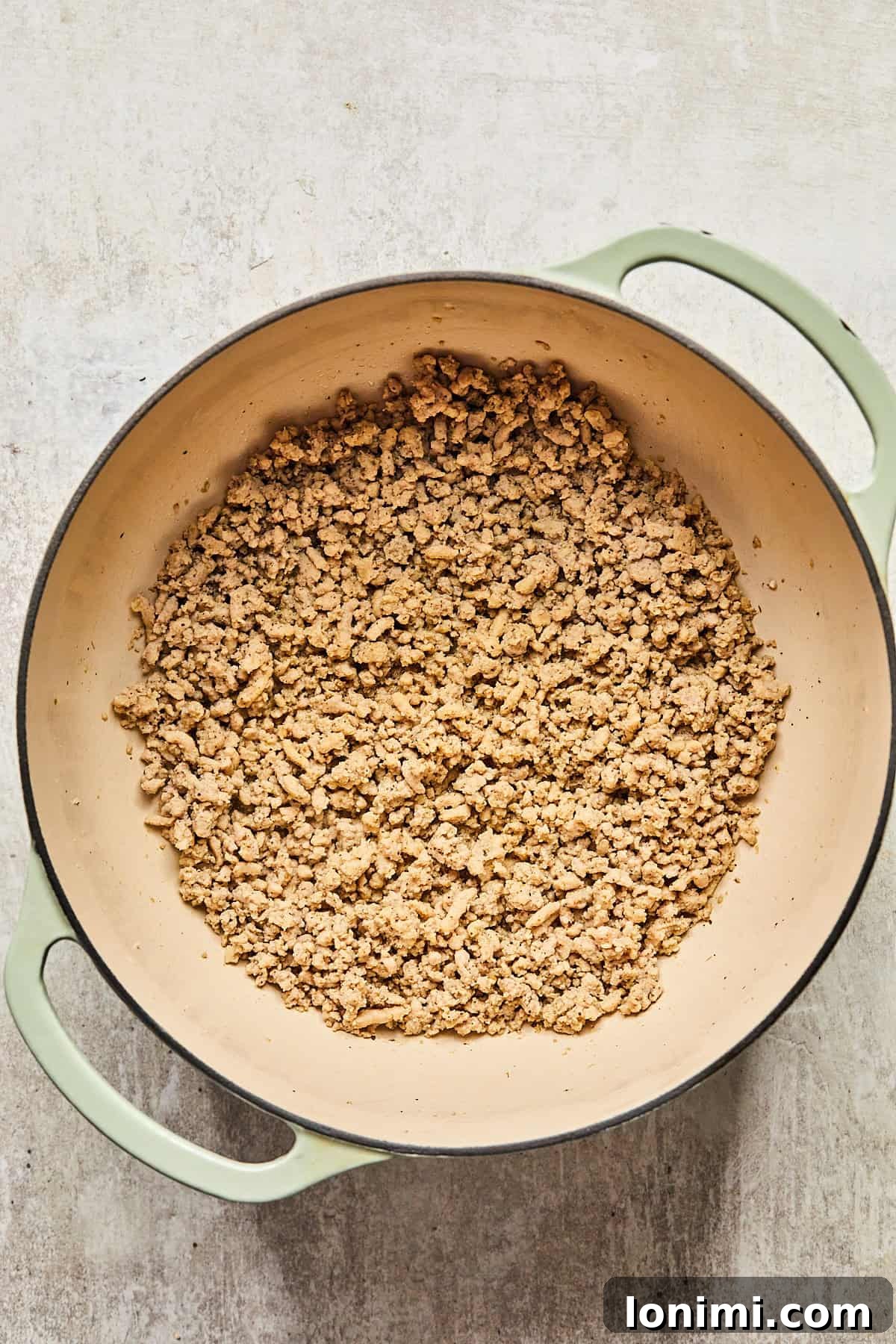 Cooked, crumbled ground turkey in a pot, ready to be removed.