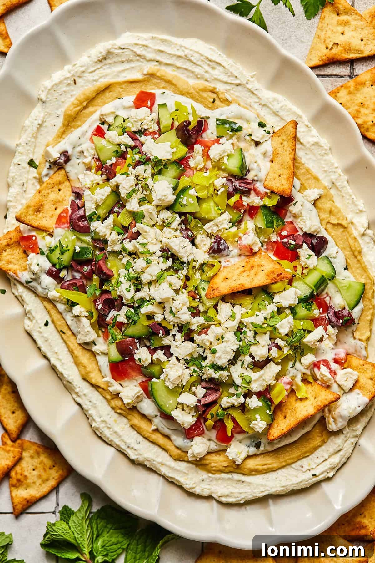 Effortless Mediterranean Layered Feta Dip 2 7 layer Greek dip on a platter with pita chips