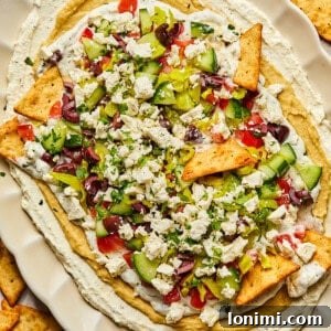 7 layer Greek dip on a platter with pita chips