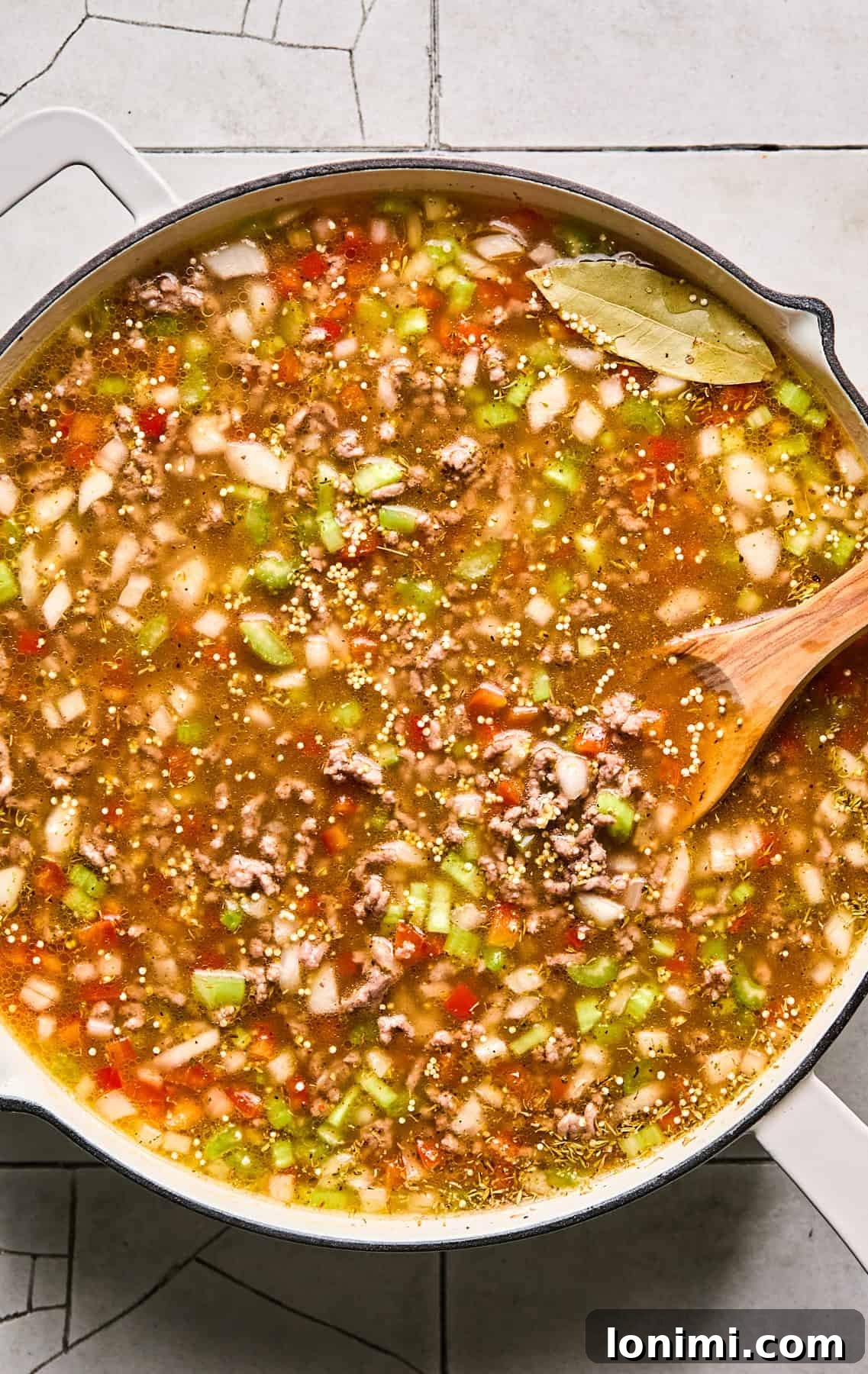 The Dirty Quinoa ingredients simmering gently in a covered skillet, allowing flavors to meld and quinoa to cook.