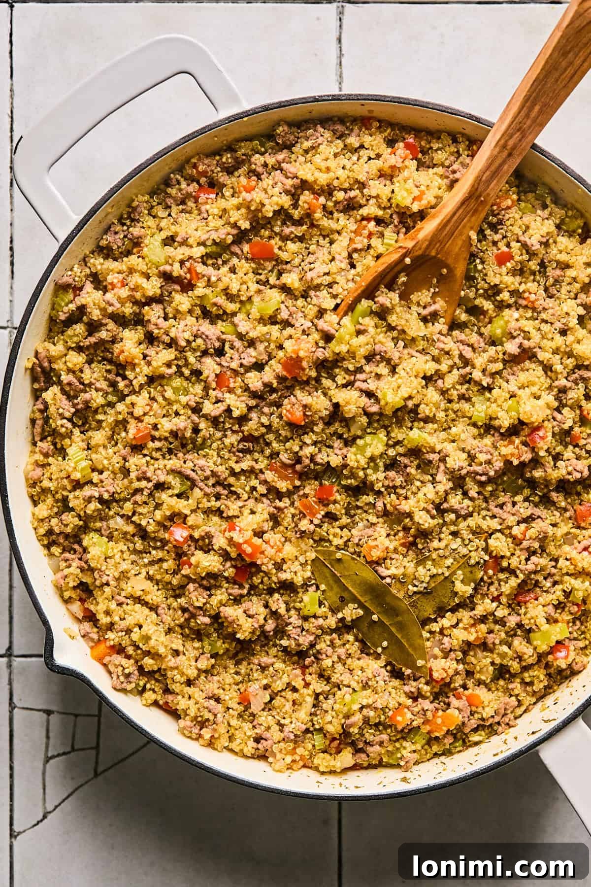 Carefully removing the bay leaves from the finished Dirty Quinoa dish, preparing it for serving.