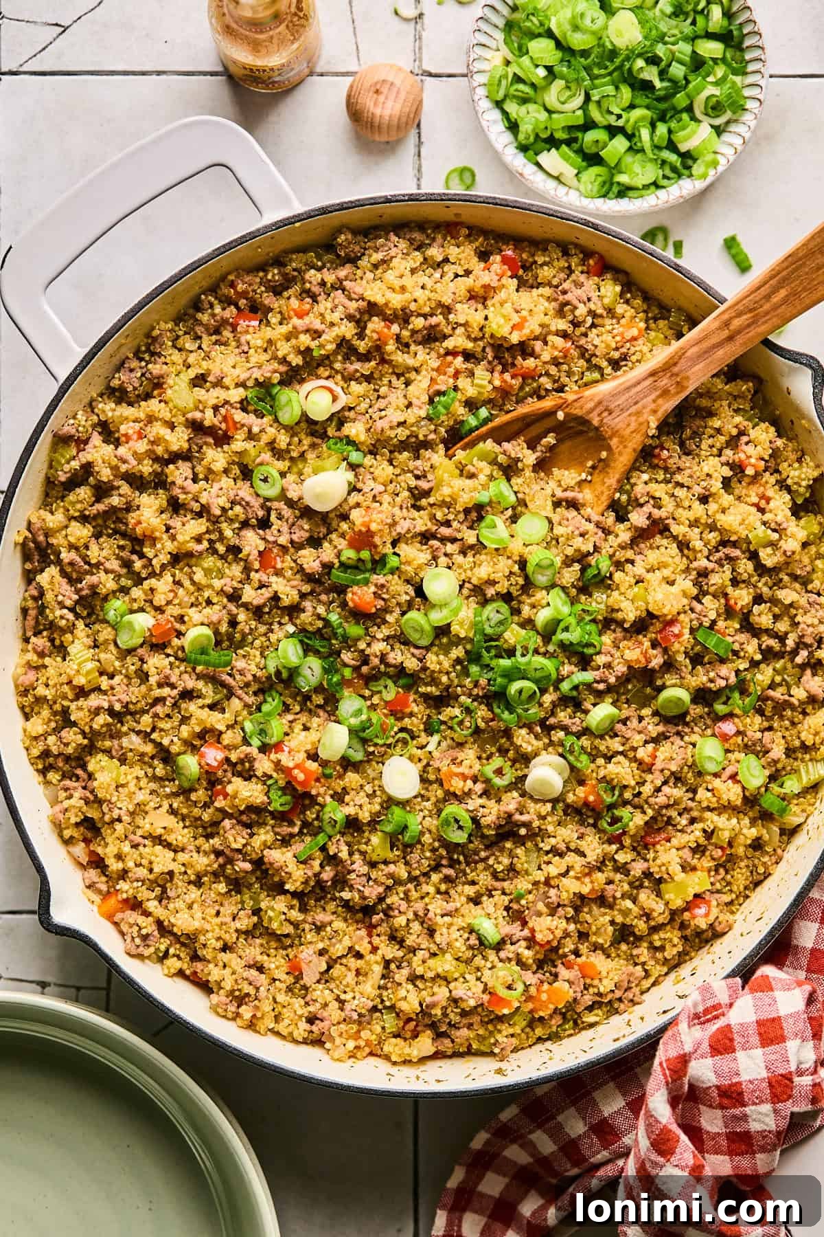Finishing the Dirty Quinoa with a generous sprinkle of freshly chopped green onions, adding color and freshness.