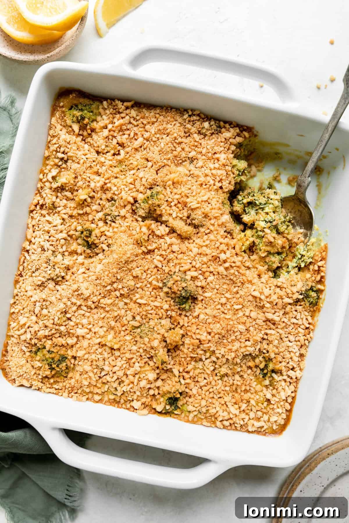 gluten free broccoli casserole in a white dish with a silver spoon scooping out a serving