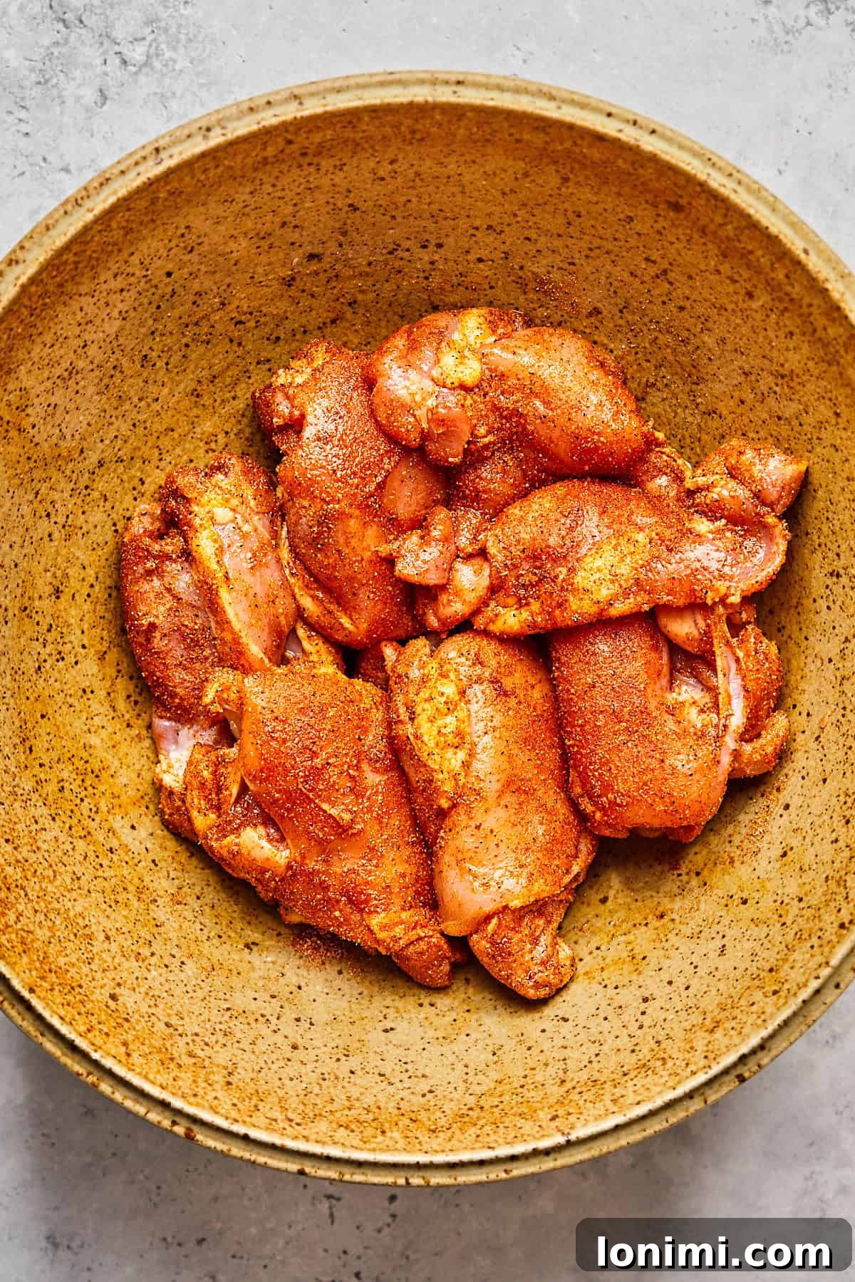 A pristine, seasoned boneless chicken thigh, expertly coated in a rich blend of spices, rests prepared for air frying.