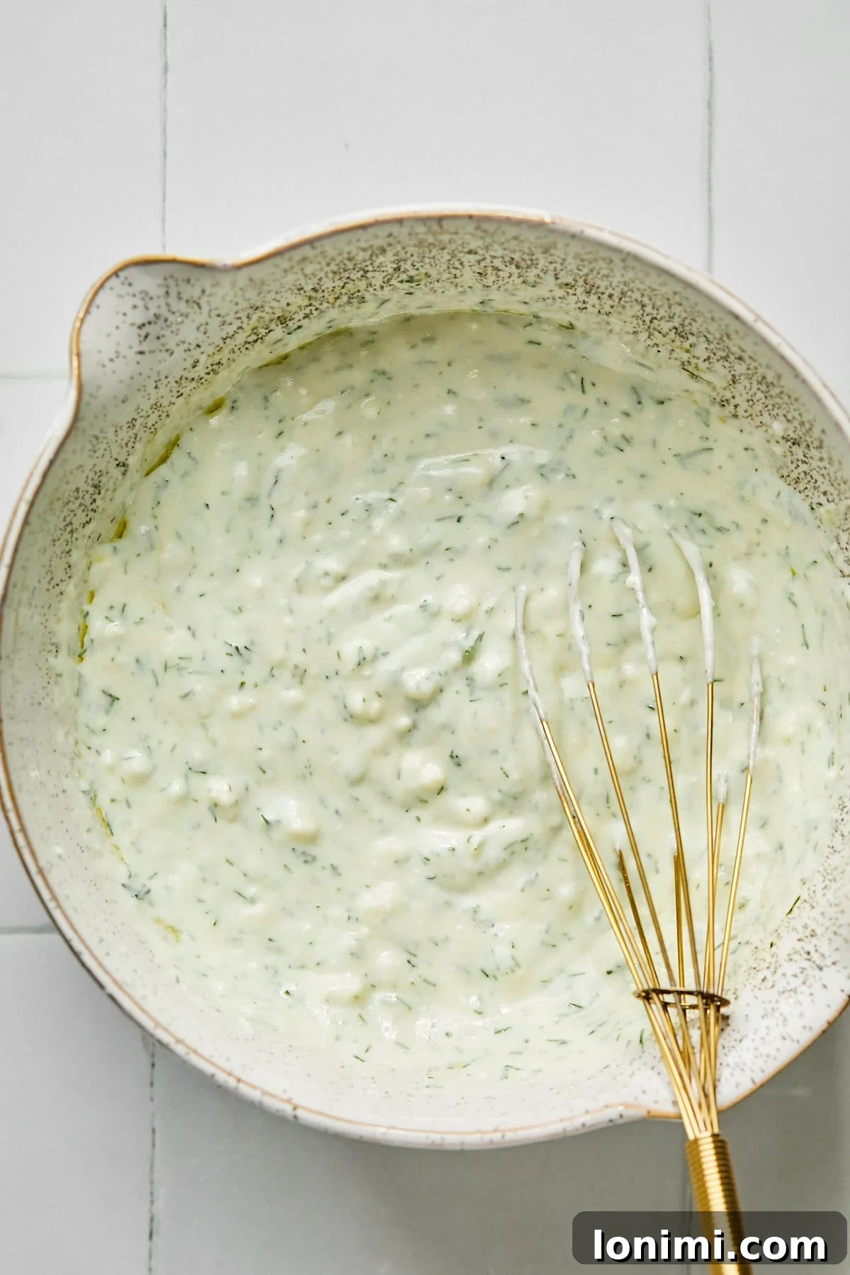 dill yogurt sauce with a gold whisk
