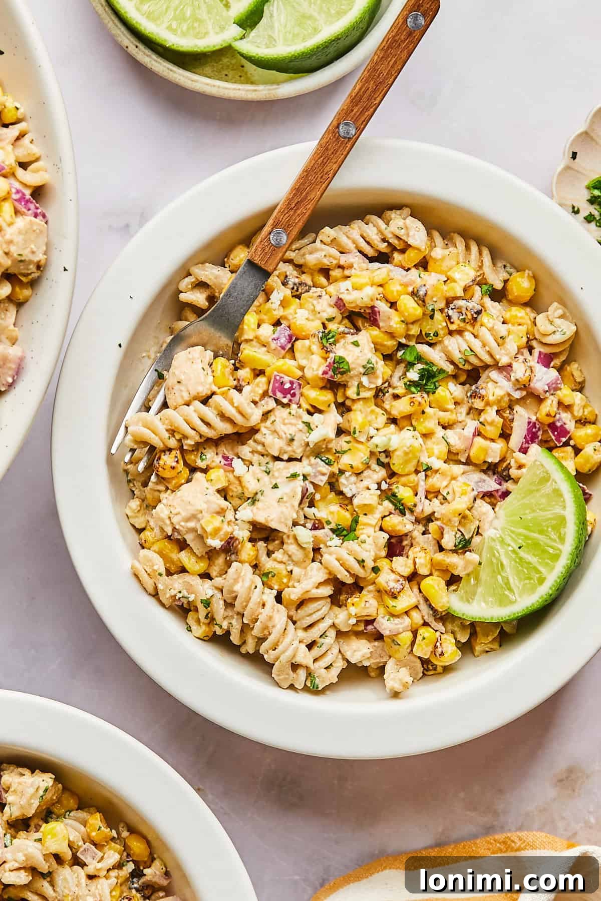 A vibrant bowl of Street Corn Pasta Salad, showcasing the creamy dressing, colorful corn, and tender chicken, ready to be enjoyed with a wooden fork.