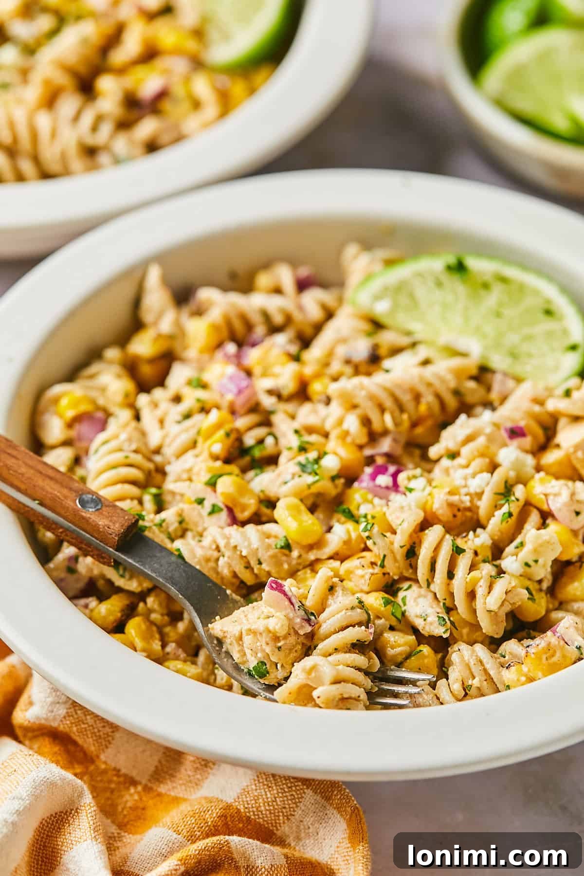 A delectable side view of Mexican street corn pasta salad, highlighting its creamy texture and colorful ingredients in a white bowl.