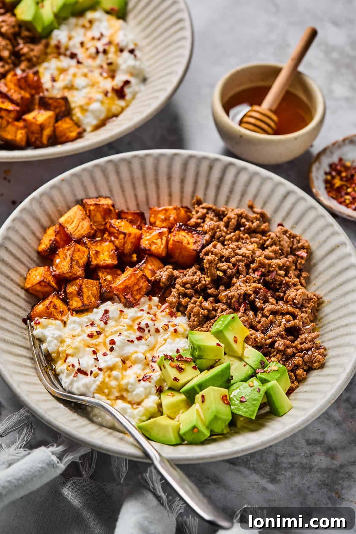 The Trending Protein Power Cottage Cheese Taco Bowl 7 a cottage cheese taco bowl in a bowl with ground beef, avocado, sweet potatoes, and hot honey with red pepper flakes.