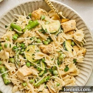 Boursin chicken pasta with spring veggies in a bowl with a gold fork
