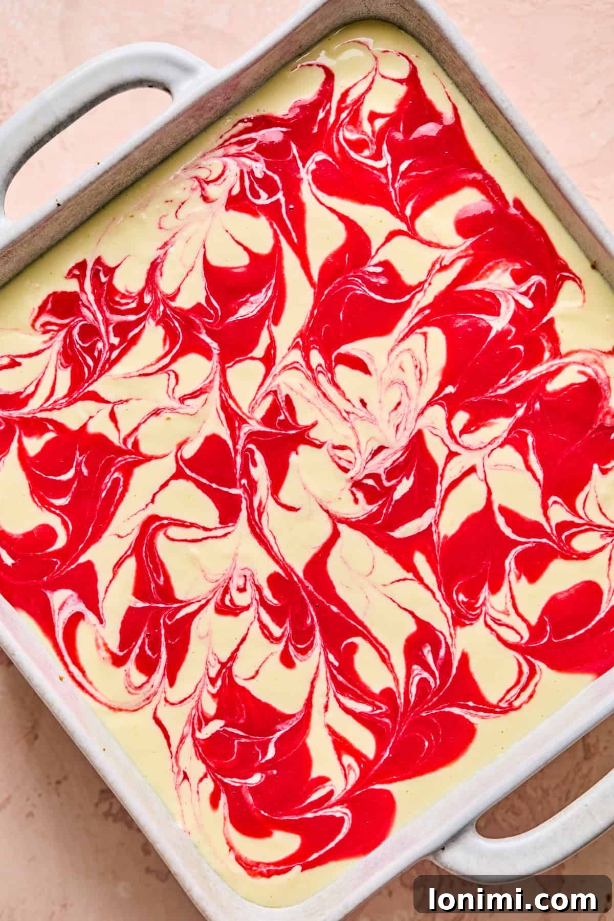 The top of the cheesecake batter featuring a beautiful, intricate swirl of raspberry puree, captured before or after baking, showcasing its marbled design.