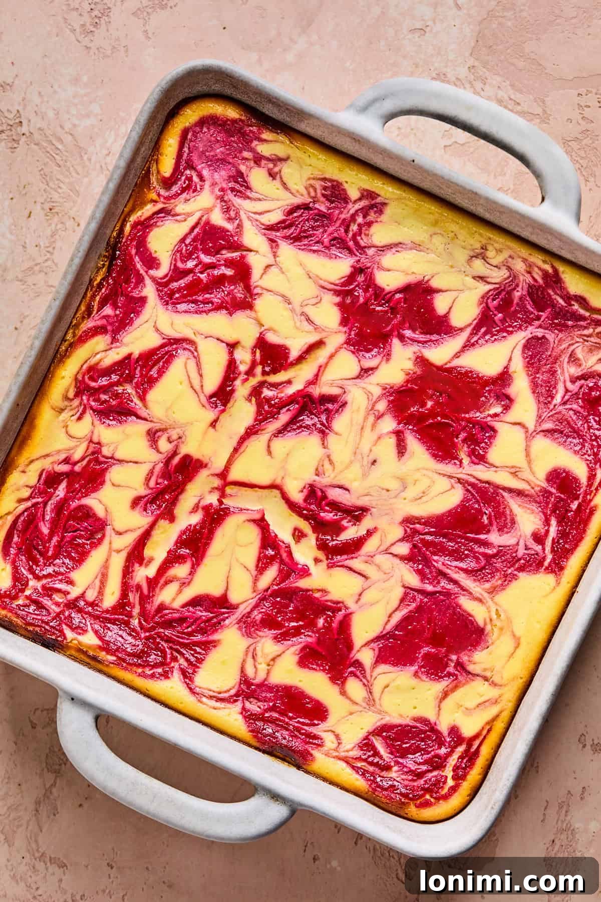 A baked protein cheesecake, golden and set, resting in a square pan after cooling, showcasing its readiness for the next steps of chilling and slicing.