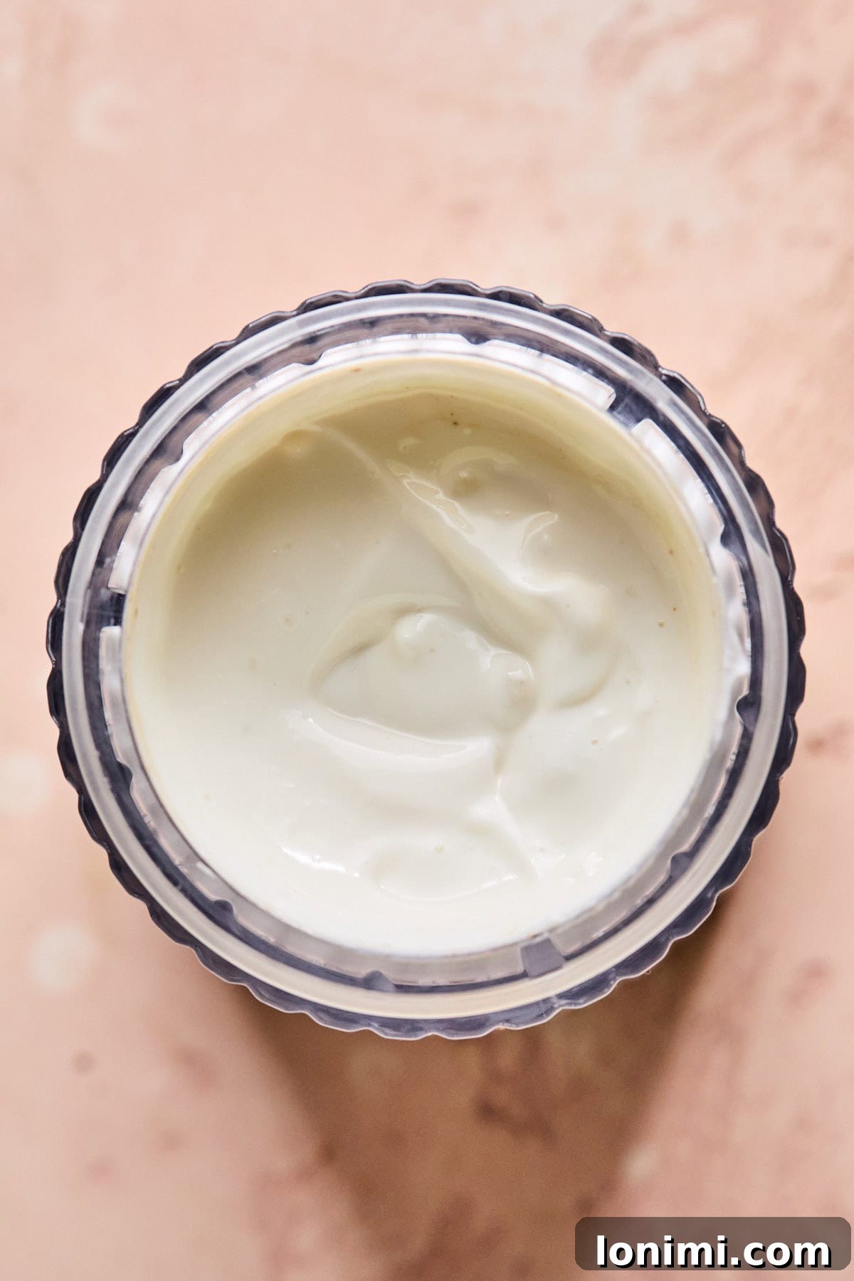 Close-up of creamy cottage cheese being blended to a smooth consistency in a blender cup, demonstrating the transformation for the cheesecake filling.