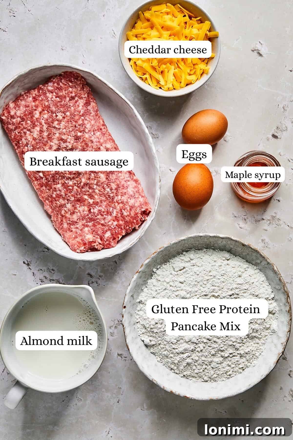 Ingredients laid out for McGriddle muffins, including savory breakfast sausage, protein pancake mix, eggs, almond milk, shredded cheddar, and maple syrup.