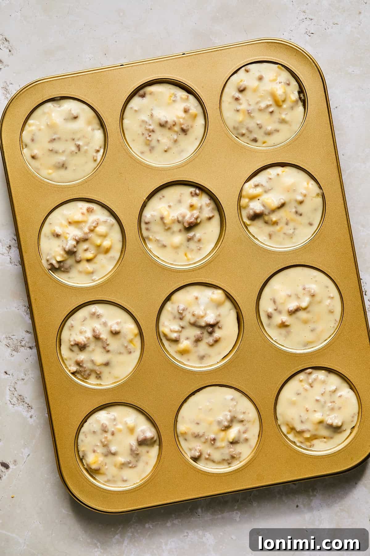 Dividing McGriddle muffin batter evenly into a greased muffin tin