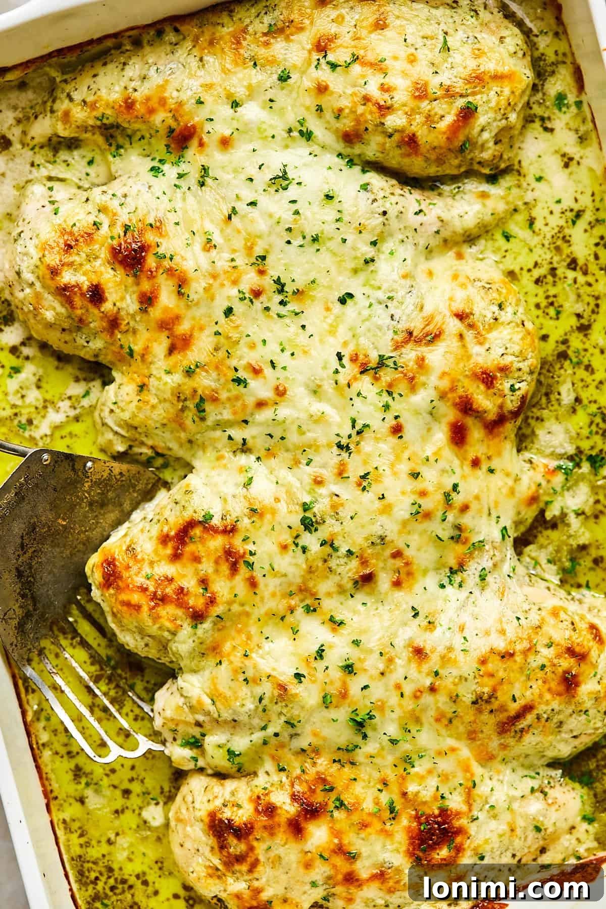 Cheesy pesto chicken bake fresh out of the oven with golden melted mozzarella on top